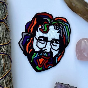 May include: A colorful embroidered patch of a man's face, a sage smudge stick, a clear quartz crystal, a pink heart-shaped crystal, and a cluster of amethyst crystals.