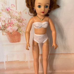 Dieses weiße Dessous-Set für VT18 Miss Revlon beinhaltet BH, Unterwäschehöschen und Nylonstrumpfschlauch
