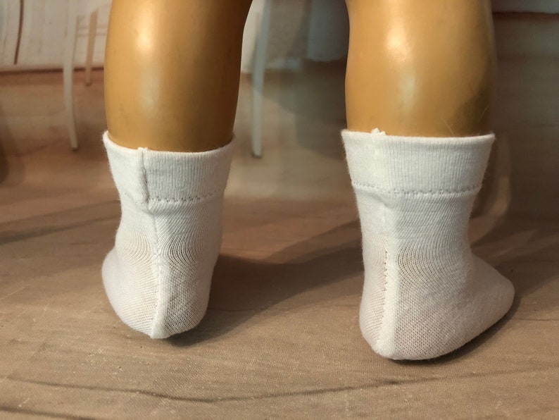 May include: A pair of white ankle socks with a seam down the back of each sock.
