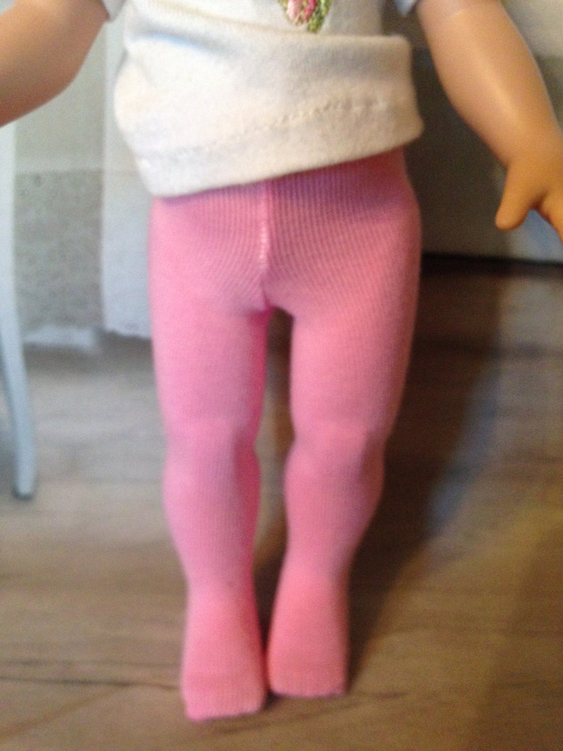 May include: Pink tights for a doll, made of a soft, stretchy fabric. The tights are a solid color and have a smooth finish.