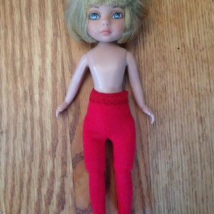 May include: A doll with blonde hair and blue eyes wearing a red pair of tights.
