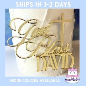 May include: A gold-colored cake topper with the words "God Bless DAVID" and a cross design. The topper is placed on a white frosted cake. The image also includes the text "MORE COLORS AVAILABLE".