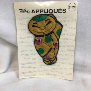May include: A vintage Talon appliquéd patch featuring a smiling cartoon character with a green hat and colorful polka dots. The patch is on a white backing with the words "Talon APPLIQUÉS" printed on it.