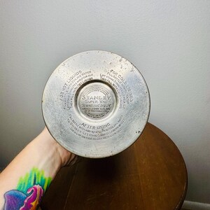 May include: A vintage Stanley Super Vac thermos bottom, featuring instructions for hot and cold liquids. The metal base has circular text and a central logo. The thermos is resting on a wooden surface.
