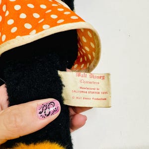May include: A vintage black plush toy with an orange and white polka dot hat. The tag reads "Walt Disney Characters" and "Manufactured by CALIFORNIA STUFFED TOYS".