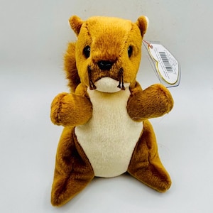 May include: A brown and white plush squirrel toy with a red and white tag attached. The squirrel has a long, bushy tail and a cute, friendly face.