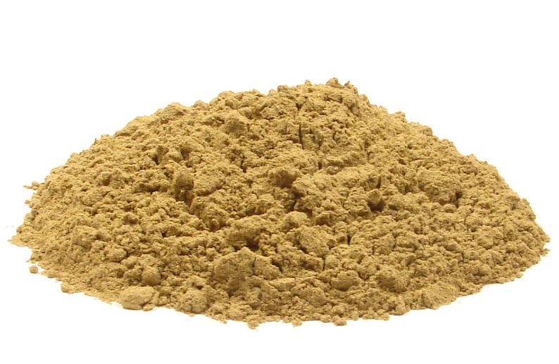 May include: A pile of light brown powder against a white background. The powder has a fine, granular texture and appears to be a natural substance. The image is well-lit, highlighting the texture and color of the powder.
