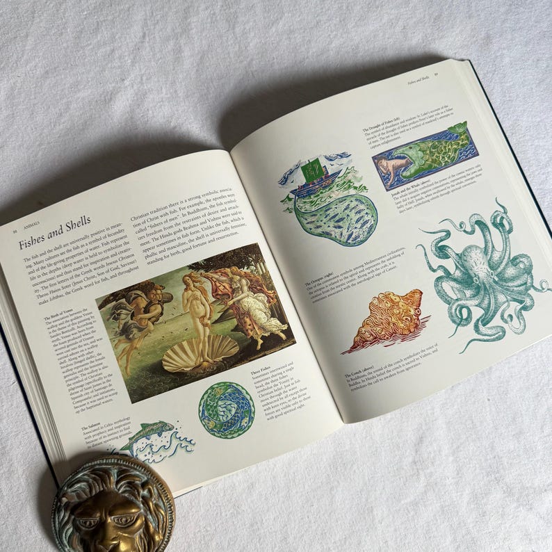 May include: An open book displaying the title "Fishes and Shells" with various illustrations. The pages show drawings of an octopus, a seashell, and a classical painting. A decorative lion head is visible at the bottom of the image.