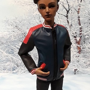 Pu&ograve; includere: Una bambola che indossa una giacca bomber blu e rossa con jeans neri e scarpe da ginnastica rosse. La bambola ha i capelli corti, neri e ricci e gli occhi marroni.