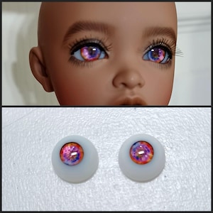 May include: A pair of pink and purple doll eyes with a galaxy design. The eyes are on a white background.