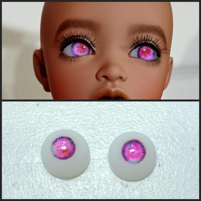 May include: Two pink and white doll eyes with a galaxy-like pattern. The eyes are on a white background.