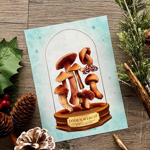 May include: A print featuring a collection of brown and tan mushrooms under a glass dome. The base of the dome has the text "Fool's Webcap" and scientific names. The background is a light blue with diamond shapes.