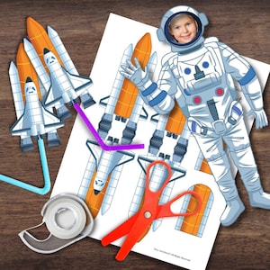 May include: A printable craft activity featuring a space-themed astronaut cutout with a hole for a face, along with multiple space shuttle cutouts. The craft requires scissors, tape, and straws to assemble. The text "Say Activities. All Rights Reserved." is at the bottom of the page.