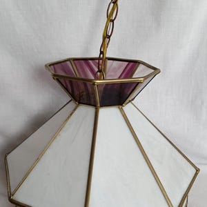 May include: A white and purple stained glass ceiling light fixture with a gold metal frame and chain.