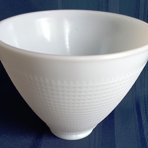May include: A white, cone-shaped bowl with a textured, grid-like pattern on the lower half. The bowl has a smooth, rounded rim and a small, circular base. The bowl is made of a solid, opaque material.
