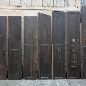May include: Nine dark brown wooden panels, each with a raised panel design, are arranged horizontally against a white wall. The panels are all the same size and shape, and they are evenly spaced.