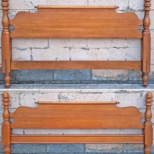 May include: A wooden headboard and footboard set featuring a warm brown finish. Both pieces have tall, turned posts with rounded finials at the top and bottom, and a horizontal top rail with a decorative rod detail across the center panel.