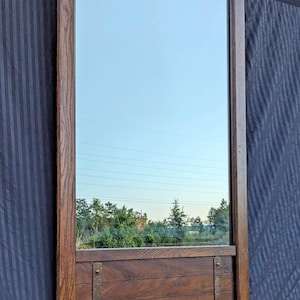 May include: A large, rectangular mirror with a dark wood frame and a wooden shelf below the mirror. The shelf has two metal brackets on each side.