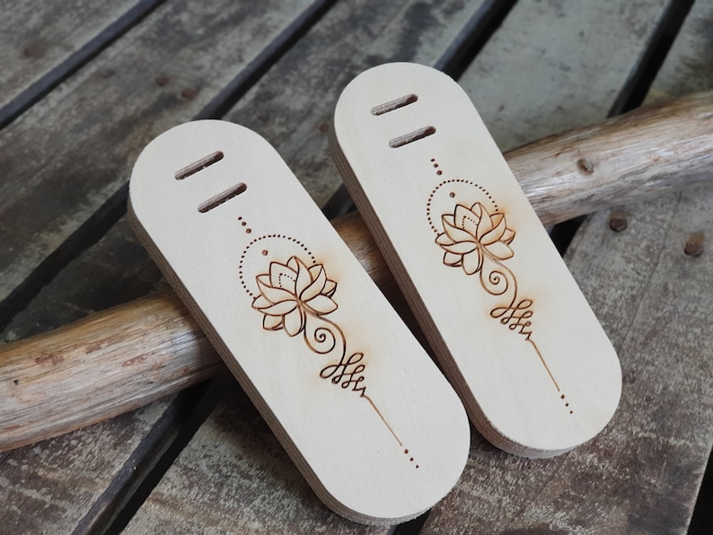 May include: Two wooden tags with a burned-in design of a lotus flower and a mandala. The tags have two holes at the top.