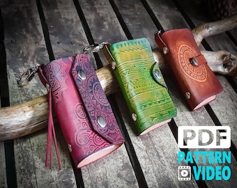 May include: Three leather keychains with different patterns and colors. The keychain on the left has a red and pink paisley pattern, the middle keychain has a green and yellow geometric pattern, and the keychain on the right has a brown leather with a circular pattern.  The keychains have metal rings and snaps.