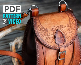 Puede incluir: Un bolso de cuero marrón cruzado con un diseño de mandala detallado. El bolso tiene un cierre de hebilla y una correa larga ajustable.