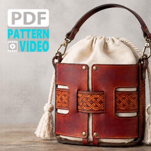 May include: A bucket bag featuring a cream-colored fabric drawstring pouch encased in a structured, dark brown leather frame with intricate Celtic knot embossing. The bag includes a leather handle, metal hardware, and thick cream rope tassels. Text reads PDF PATTERN VIDEO.