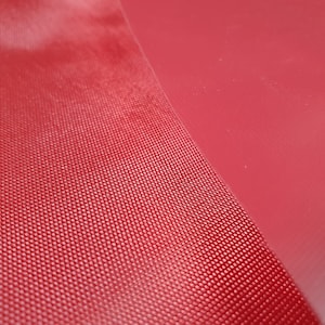 Pode incluir: Close-up de um tecido vermelho texturizado com uma superf&iacute;cie lisa vermelha ao lado.