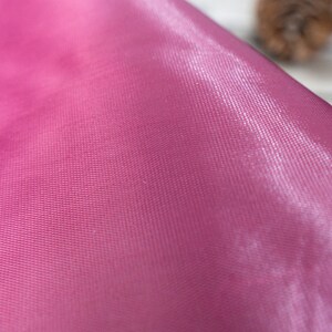 Pode incluir: Close-up de um tecido rosa liso com um padr&atilde;o texturizado sutil. O tecido tem um brilho leve e &eacute; macio ao toque.