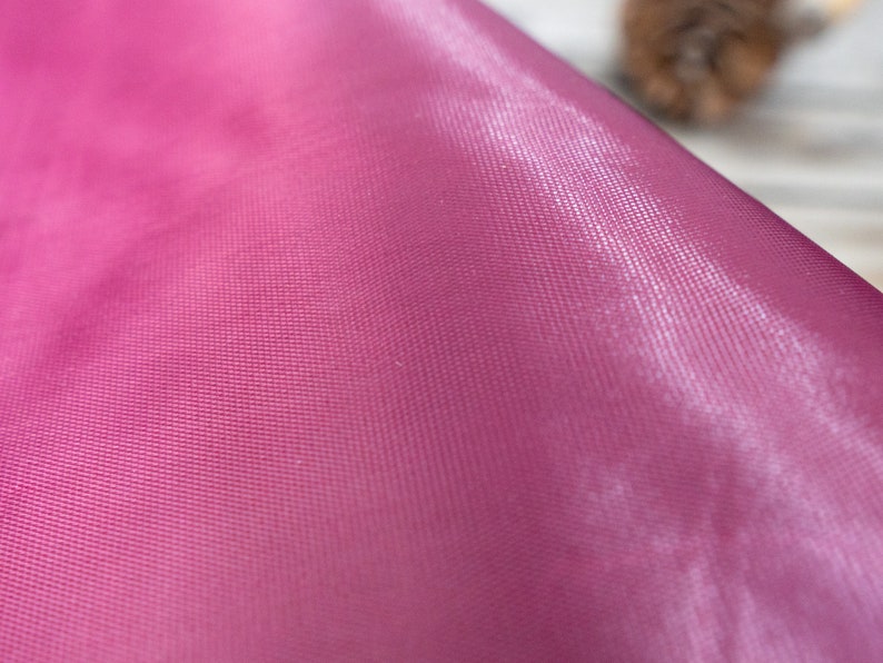 Pode incluir: Close-up de um tecido rosa liso com um padr&atilde;o texturizado sutil. O tecido tem um brilho leve e &eacute; macio ao toque.