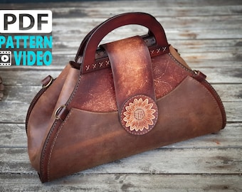 May include: A brown leather handbag with a wooden handle and a sunflower design. The bag has a flap closure and a small pocket on the side.