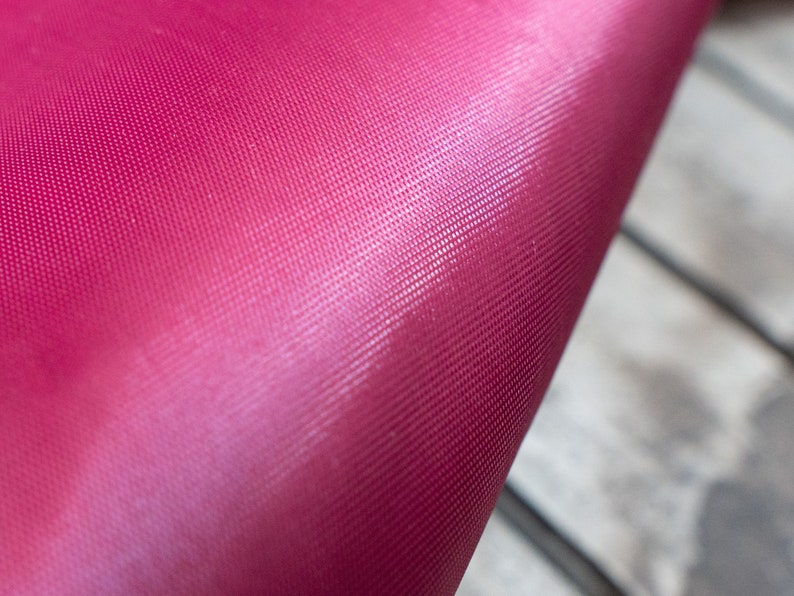 Pode incluir: Close-up de um tecido rosa brilhante com um padr&atilde;o texturizado sutil. O tecido &eacute; liso e tem um leve brilho.