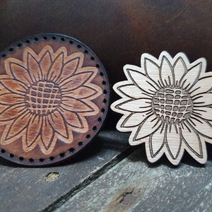 May include: Two wooden sunflower designs, one with a brown wood stain and the other with a natural wood finish.