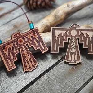 May include: Two wooden Native American eagle pendants, one with a brown leather cord and turquoise beads. The eagle designs are intricately carved and feature geometric patterns.