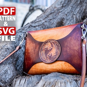 Könnte beinhalten: Eine braune Leder-Clutch mit einem silbernen Verschluss und einem langen Riemen. Die Tasche hat ein dekoratives Design mit zwei sich gegenüberstehenden Wölfen auf der Vorderseite. Der Text "PDF PATTERN & SVG FILE" ist in roten Buchstaben auf weißem Hintergrund.