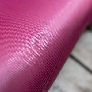 Pode incluir: Close-up de um tapete de ioga rosa escuro com uma superf&iacute;cie texturizada.