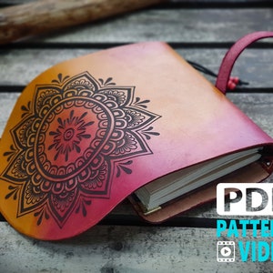 Può includere: Un diario rilegato in pelle con un design a mandala sulla copertina. Il diario è chiuso e presenta un gradiente di rosso, arancione e giallo. Il testo "PDF PATTERN VIDEO" è visibile nell'angolo in basso a destra dell'immagine.