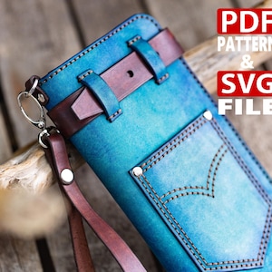 Könnte beinhalten: Eine handgefertigte blaue Ledergeldbörse mit braunem Lederriemen und Akzenten. Die Geldbörse hat ein Taschen-Design mit dekorativen Nähten und eine Handschlaufe. Der Text auf dem Bild lautet "PDF PATTERN & SVG FILE".