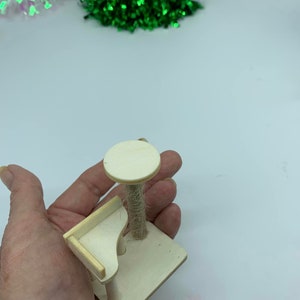 May include: A small wooden cat tree with a platform and a scratching post covered in sisal rope. The cat tree is light brown and has a simple design.