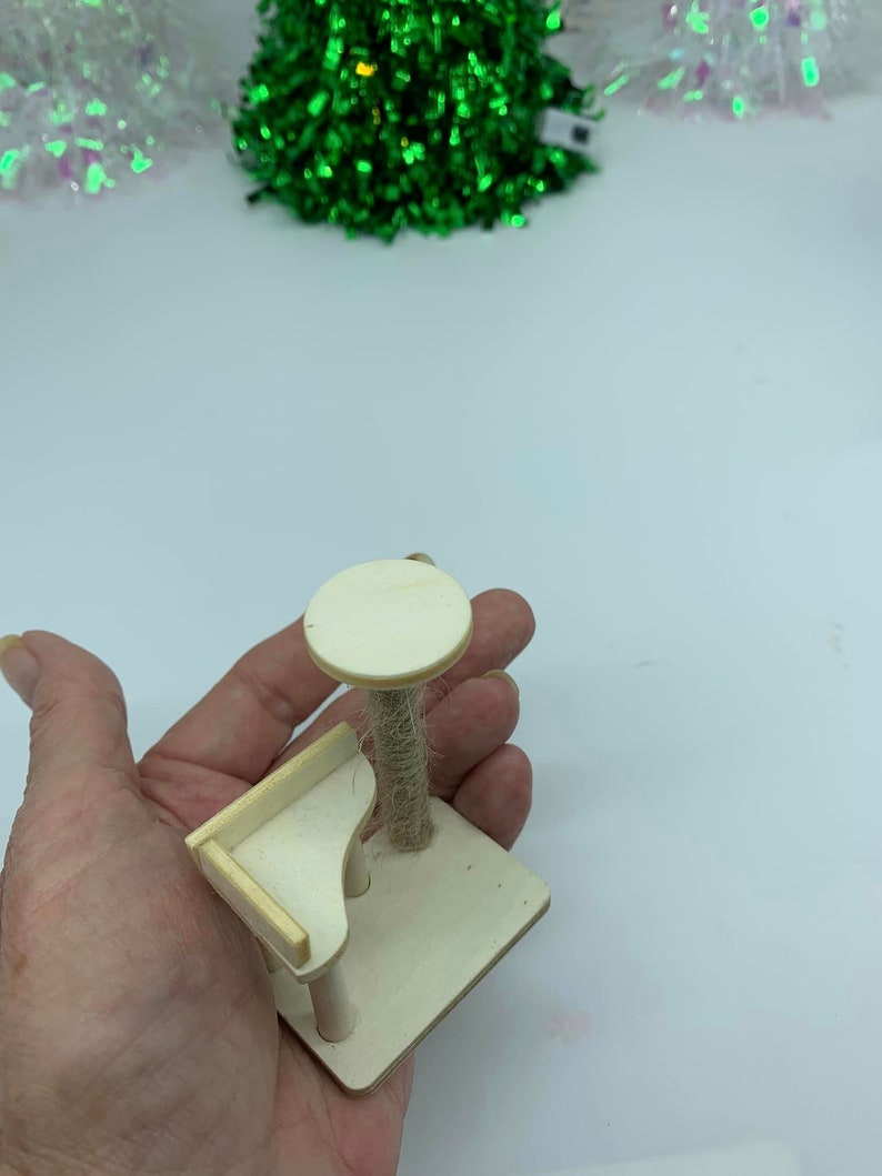 May include: A small wooden cat tree with a platform and a scratching post covered in sisal rope. The cat tree is light brown and has a simple design.