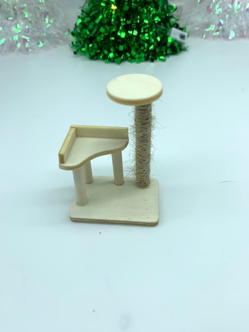 May include: A small wooden cat tree with a round platform and a scratching post covered in sisal rope.