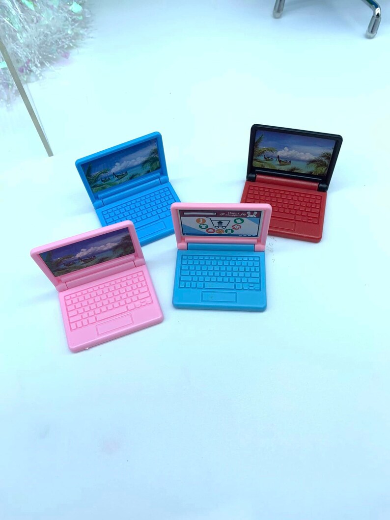 Puede incluir: Cuatro ordenadores port&aacute;tiles de juguete en diferentes colores: rosa, azul, azul claro y rojo. Cada ordenador port&aacute;til tiene una pantalla con una escena de playa y un teclado.