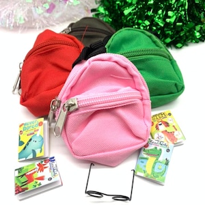 May include: Four miniature backpacks in red, green, pink, and brown with miniature books and glasses. The backpacks have zippers and are made of a soft fabric.