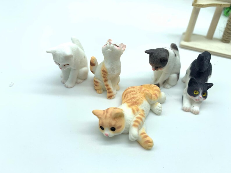 May include: Five miniature ceramic cat figurines in various poses. The cats are white, black, orange, and brown with black markings.