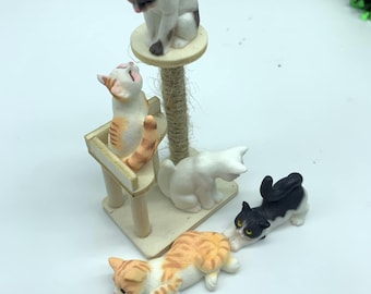Pode incluir: Um conjunto de quatro estatuetas de gato em miniatura, incluindo um gato branco com manchas pretas, um gato preto com manchas brancas, um gato branco com manchas laranja e um gato laranja com manchas brancas. Os gatos estão em várias posições de brincadeira, incluindo um gato escalando uma árvore para gatos em miniatura.