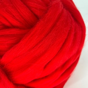 May include: A close-up of a bright red ball of yarn. The yarn is soft and fluffy, and it is perfect for knitting or crocheting.