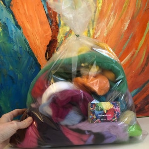 May include: A clear plastic bag filled with colorful wool roving. The bag is tied at the top and has a label that says "Shep's Wool" and "Shepwool.com". The label also says "Spin, Felt, Weave, Knit, ENJOY!"