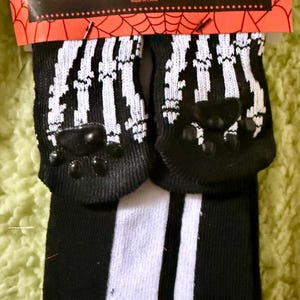 May include: Black and white matching socks for pets and their owners. The socks have a paw print design on the pet socks and vertical stripes on the owner's socks. The packaging reads "PET & OWNER SOCKS MATCHING SOCKS FOR YOU AND YOUR PET!"