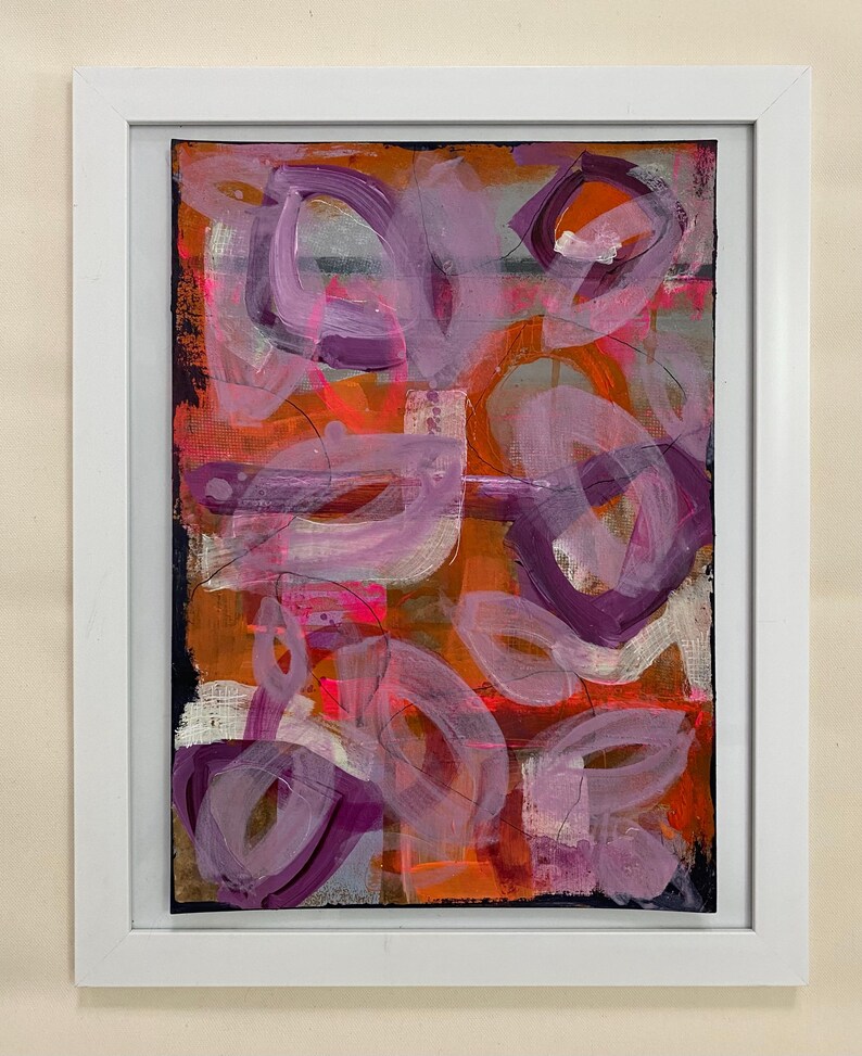 May include: Abstract painting with a mix of pink, purple, orange, and white paint. The painting has a textured look and is framed in a white frame.