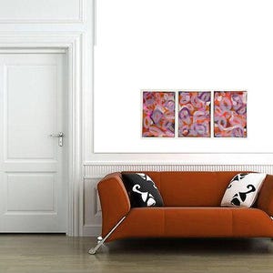 May include: Three abstract paintings with pink, orange, and purple swirls. The paintings are framed and hung on a white wall above a brown couch with black and white pillows.
