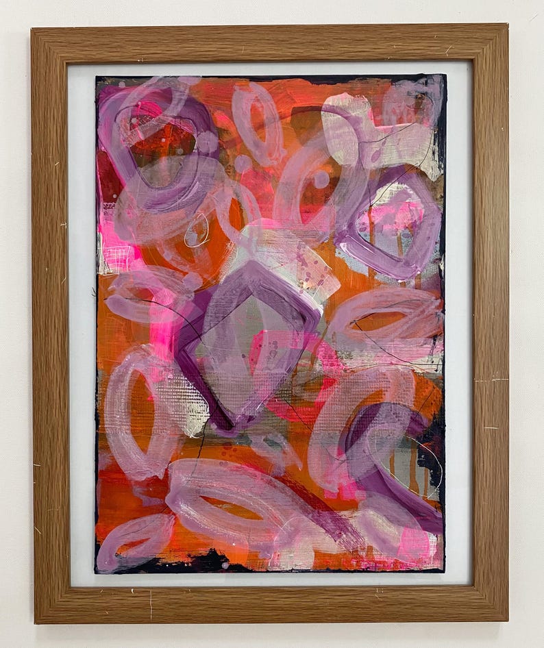 May include: Abstract painting with a bright orange background and purple and pink shapes. The painting is framed in a natural wood frame.